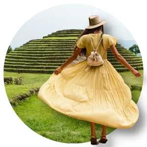 mujer de vestido amarillop largo con sombrero de espaldas en las Piramides de Guachimontones