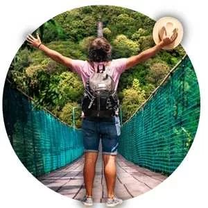 hombre de espaldas elevando los brazos sosteniendo su sombrero en un puente dentro de la naturaleza del Pueblo Magico de Mazamitla